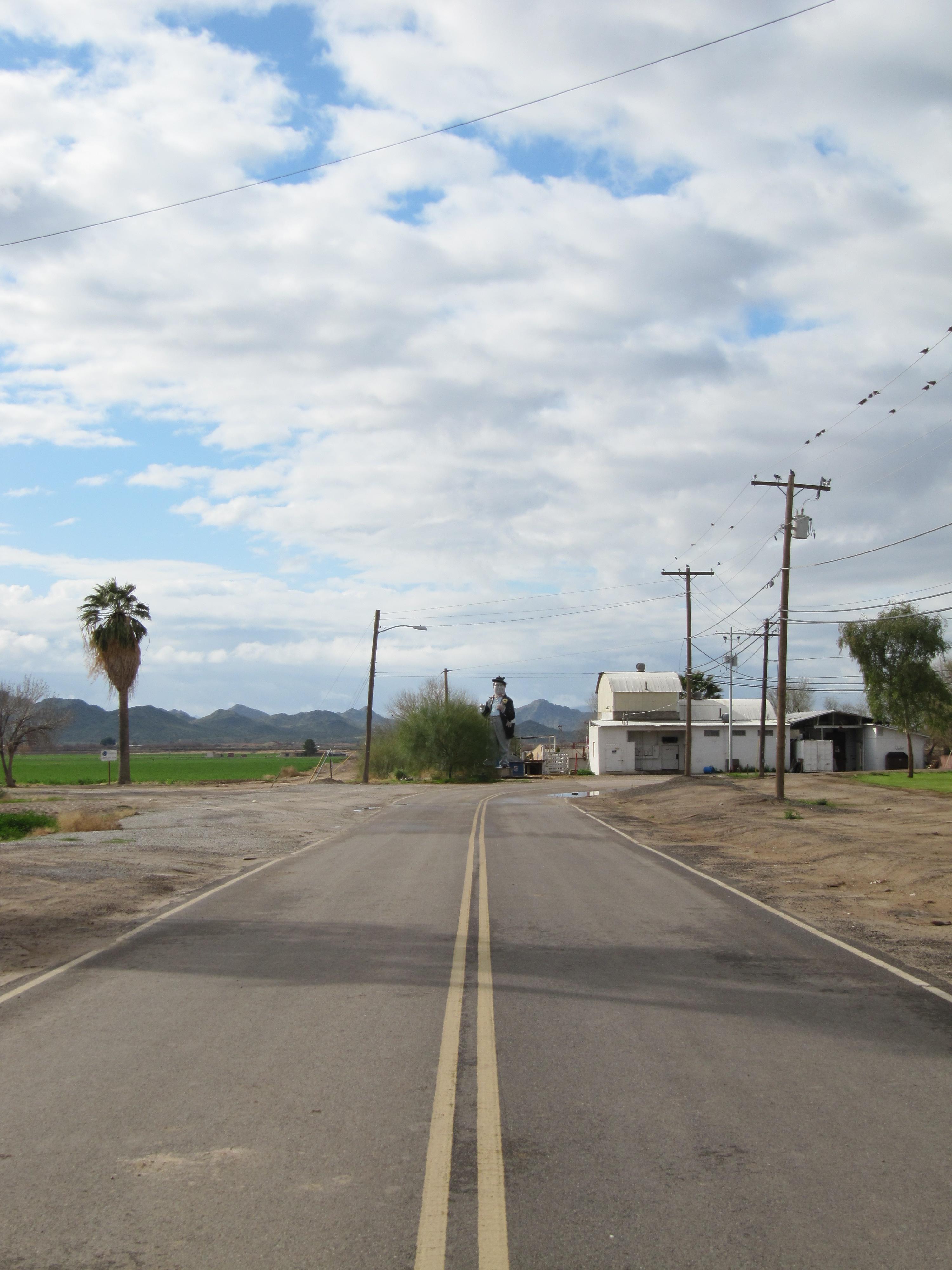 A 40 Foot Man Stands at the end of a road.