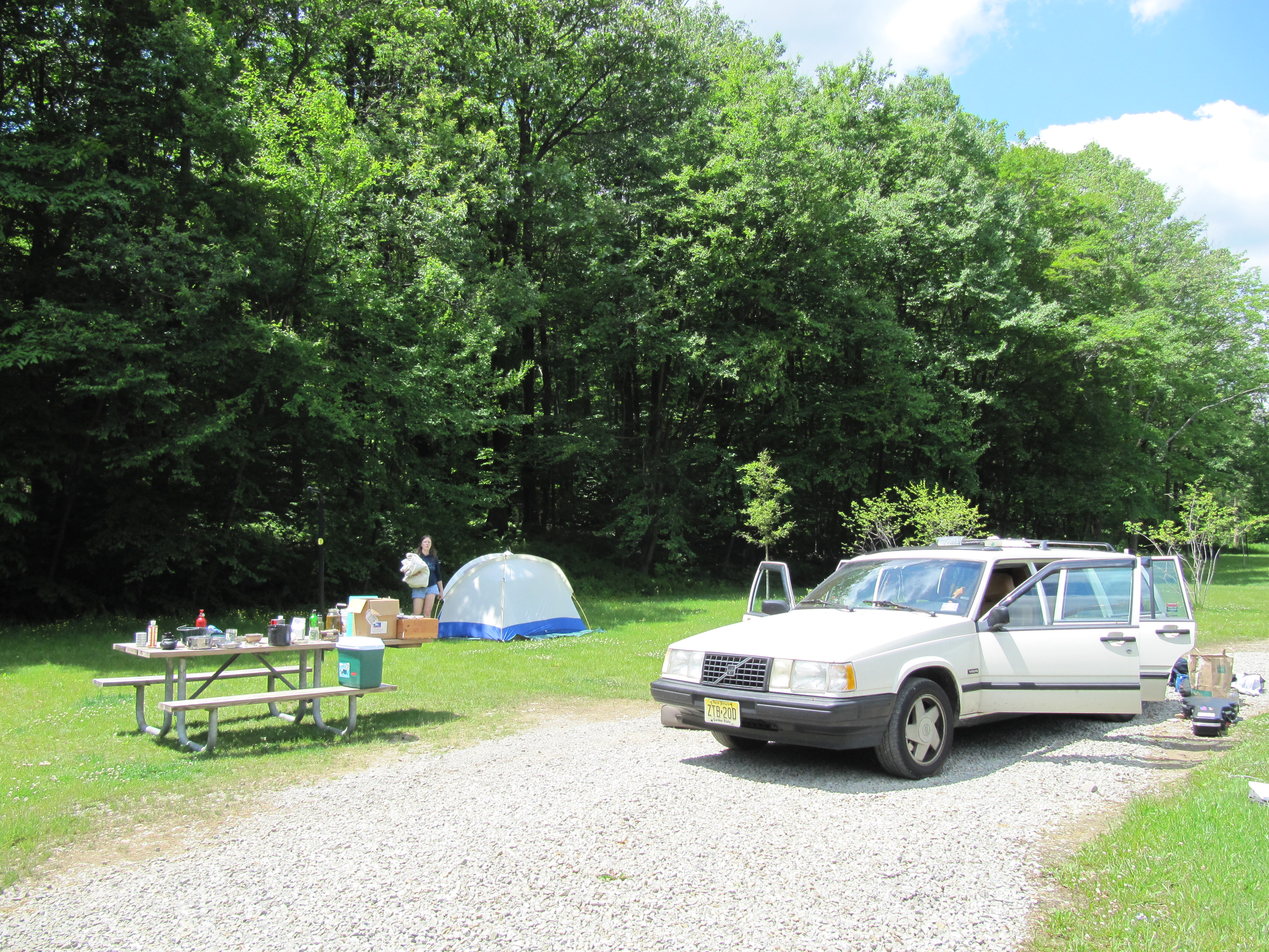 The Volvo's doors are wide open while the tent is deconstructed